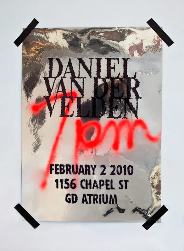 A silver foil poster taped to a wall: Daniel van der Velden, February 2 2010, 1156 Chapel St, in rough dark type, with 7pm sprayed across it in red.