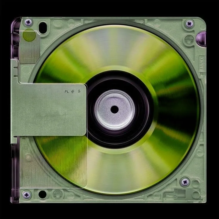 A translucent green MiniDisc cartridge photographed square-on against black, its metallic disc catching the light.