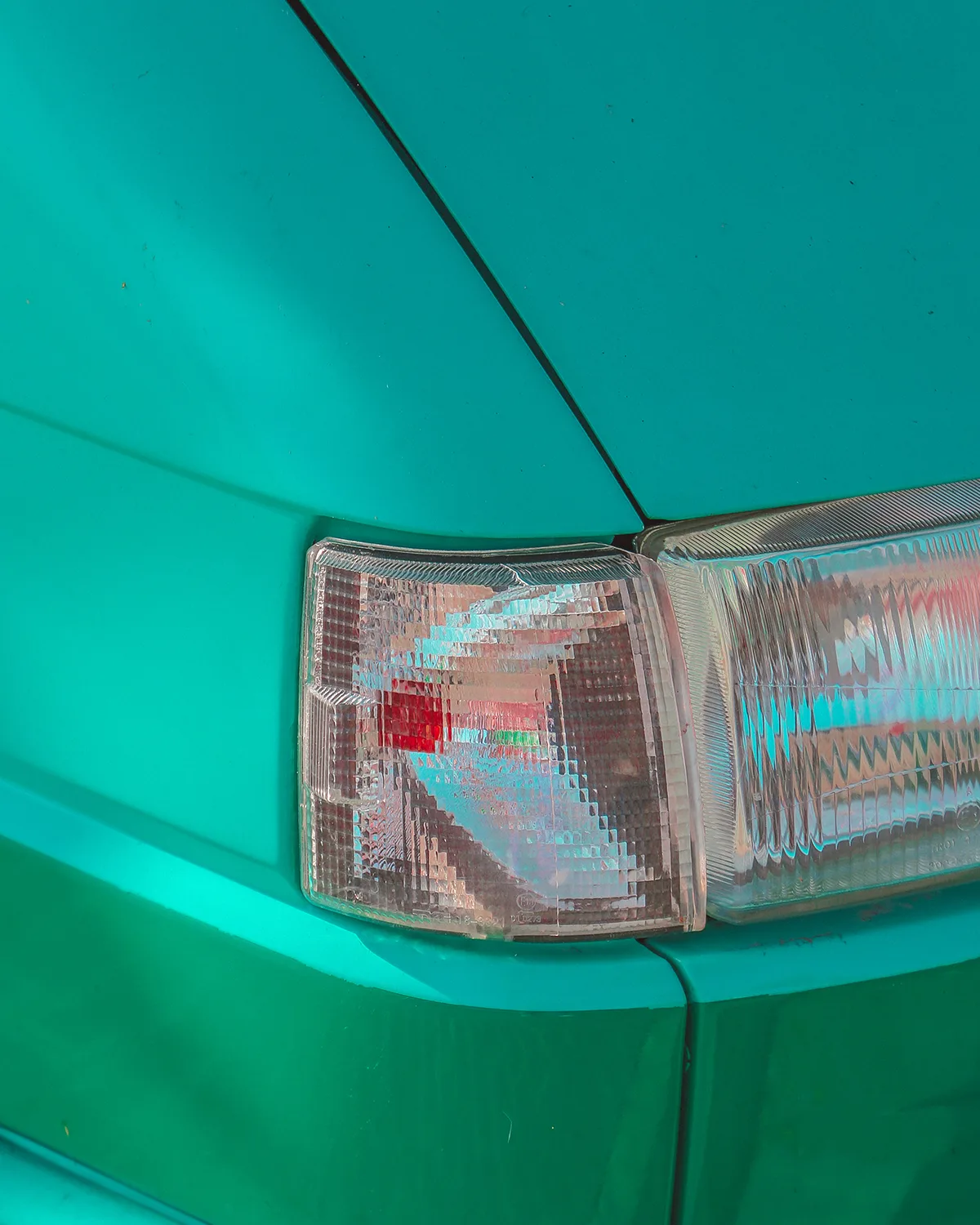 Close-up of a car's clear tail light set into a teal-green body panel.